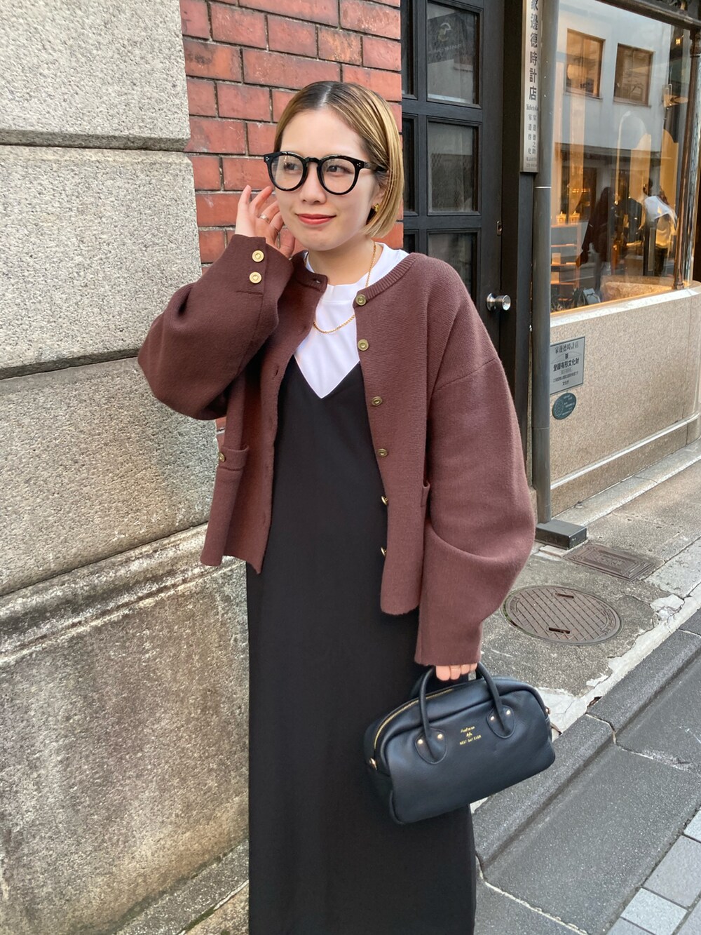 ブラック系のショルダーバッグ、ブラウン系のカーディガン/ボレロ、ブラック系のワンピースを着用したレディースの秋コーディネートの5枚目の写真