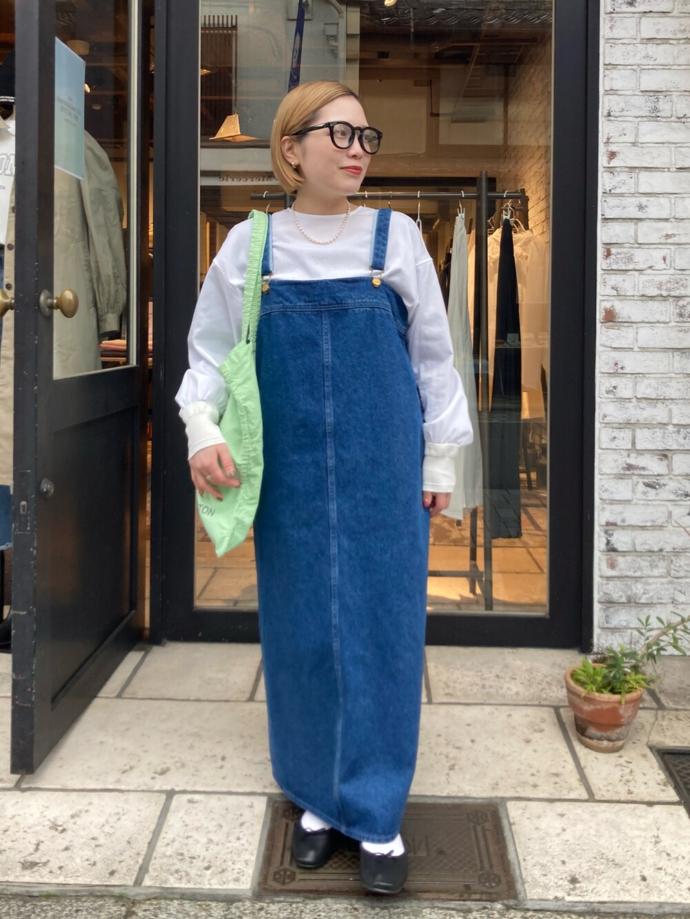 ブルー系のジャンパースカート、グリーン系のバッグ、ホワイト系のシャツ/ブラウスを着用したレディースの冬コーディネートの4枚目の写真