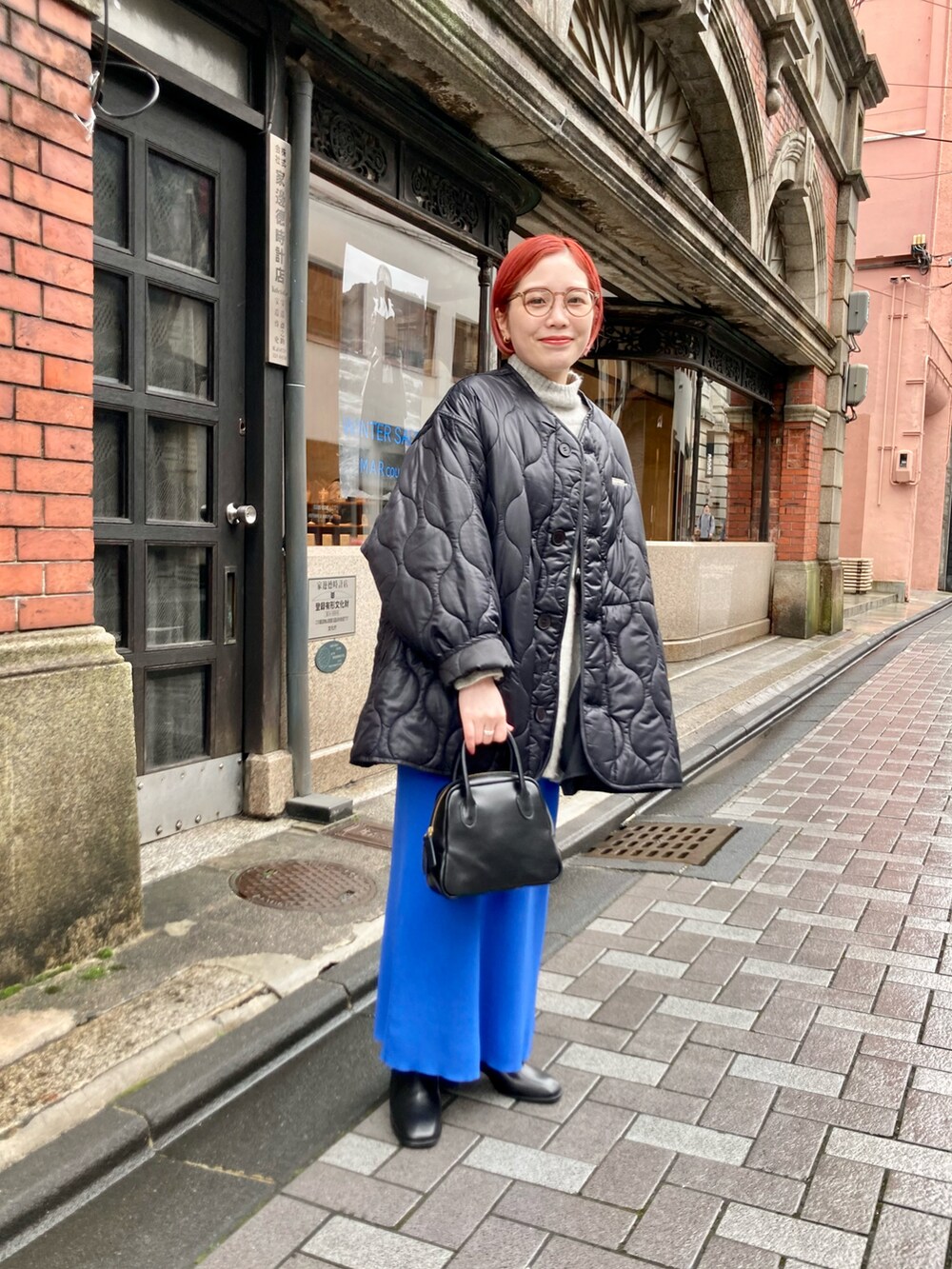 ブルー系のスカート、ブラック系のその他アウター、ベージュ系のニット/セーターを着用したレディースの冬コーディネートの2枚目の写真