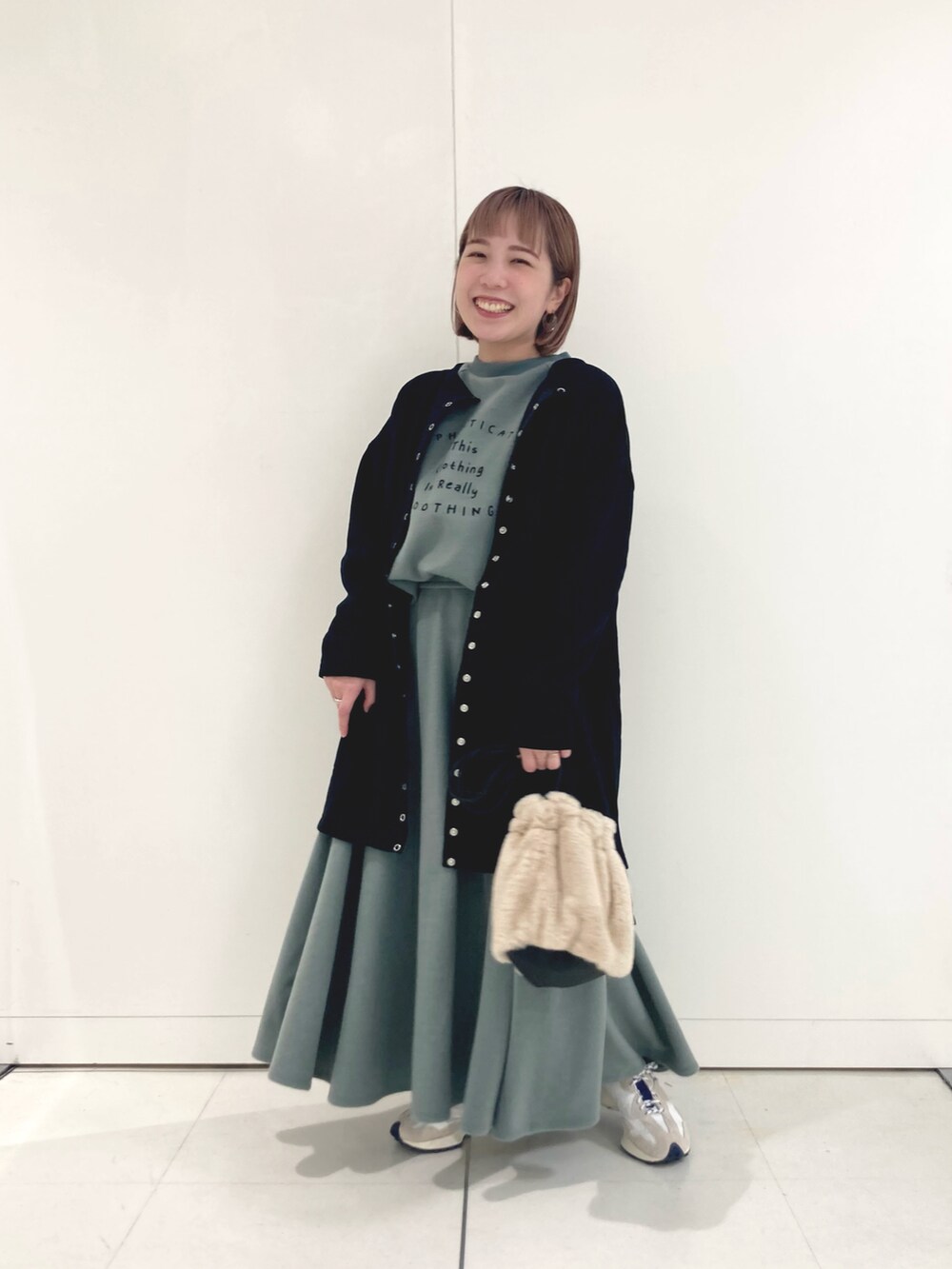 グリーン系のTシャツ/カットソー、グリーン系のスカート、ベージュ系のスニーカーを着用したレディースの秋コーディネートの4枚目の写真