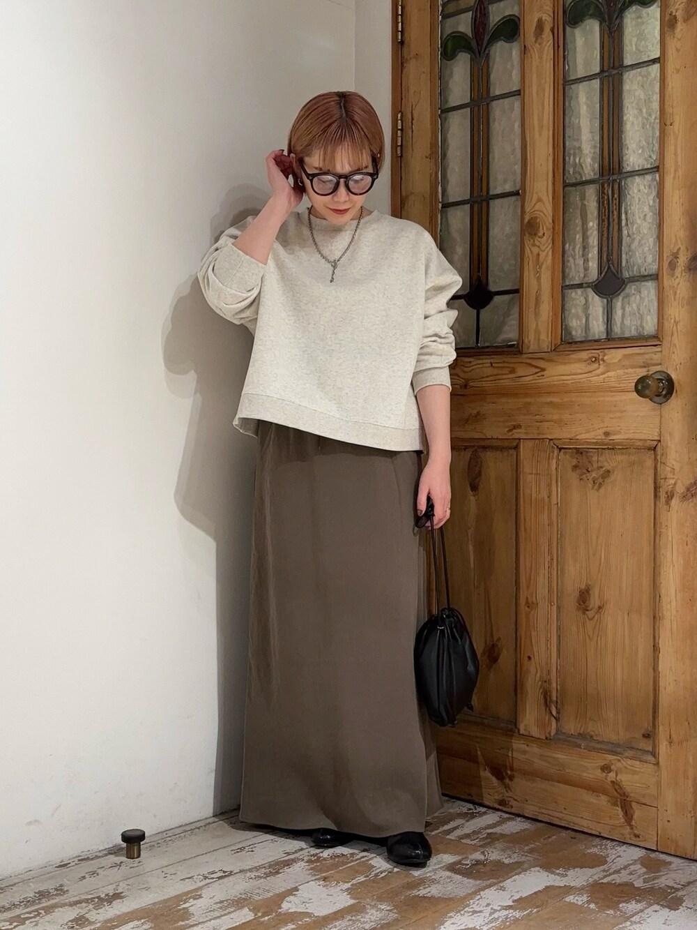 ベージュ系のTシャツ/カットソー、グリーン系のスカート、ブラック系のショルダーバッグを着用したレディースの秋コーディネートの3枚目の写真