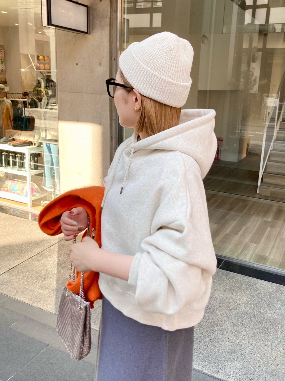 ブラック系のブーツ、グレー系のスカート、ゴールド系のショルダーバッグを着用したレディースの秋コーディネートの5枚目の写真