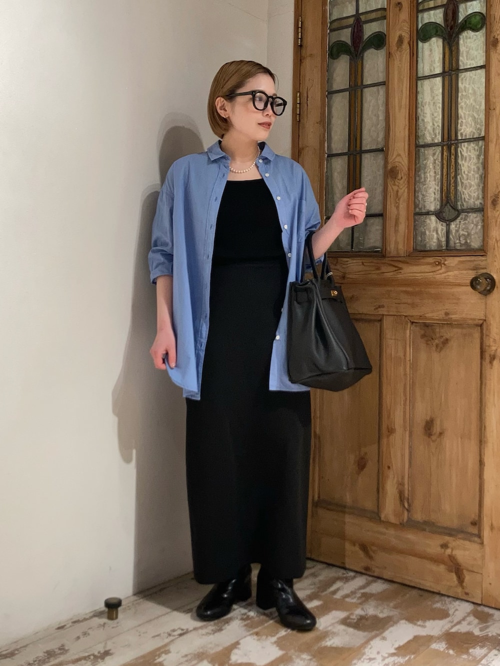 ブラック系のボストンバッグ、ブラック系のブーツ、ブラック系のスカートを着用したレディースの春コーディネートの2枚目の写真