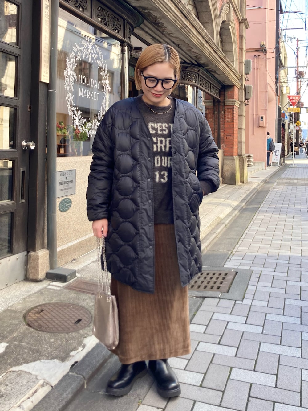 ブラック系のブーツ、ゴールド系のショルダーバッグ、ブラウン系のスカートを着用したレディースの冬コーディネートの2枚目の写真