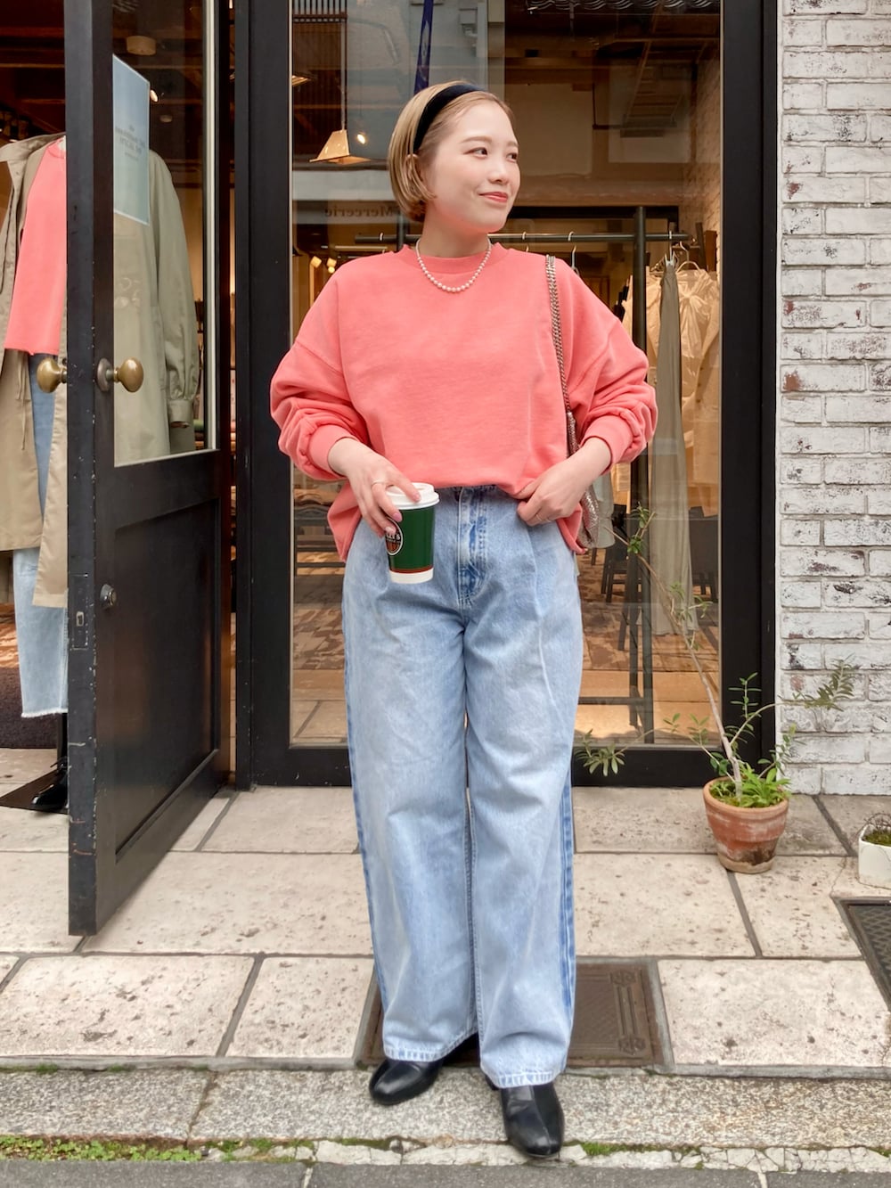 ブラック系のブーツ、ブルー系のデニムパンツ、オレンジ系のスウェットを着用したレディースの冬コーディネートの2枚目の写真