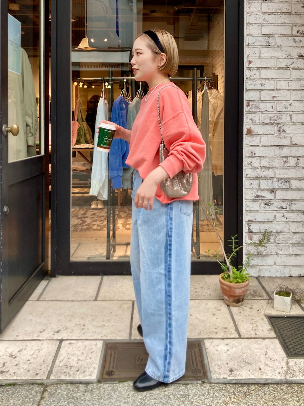 ブラック系のブーツ、ブルー系のデニムパンツ、オレンジ系のスウェットを着用したレディースの冬コーディネートの3枚目の写真