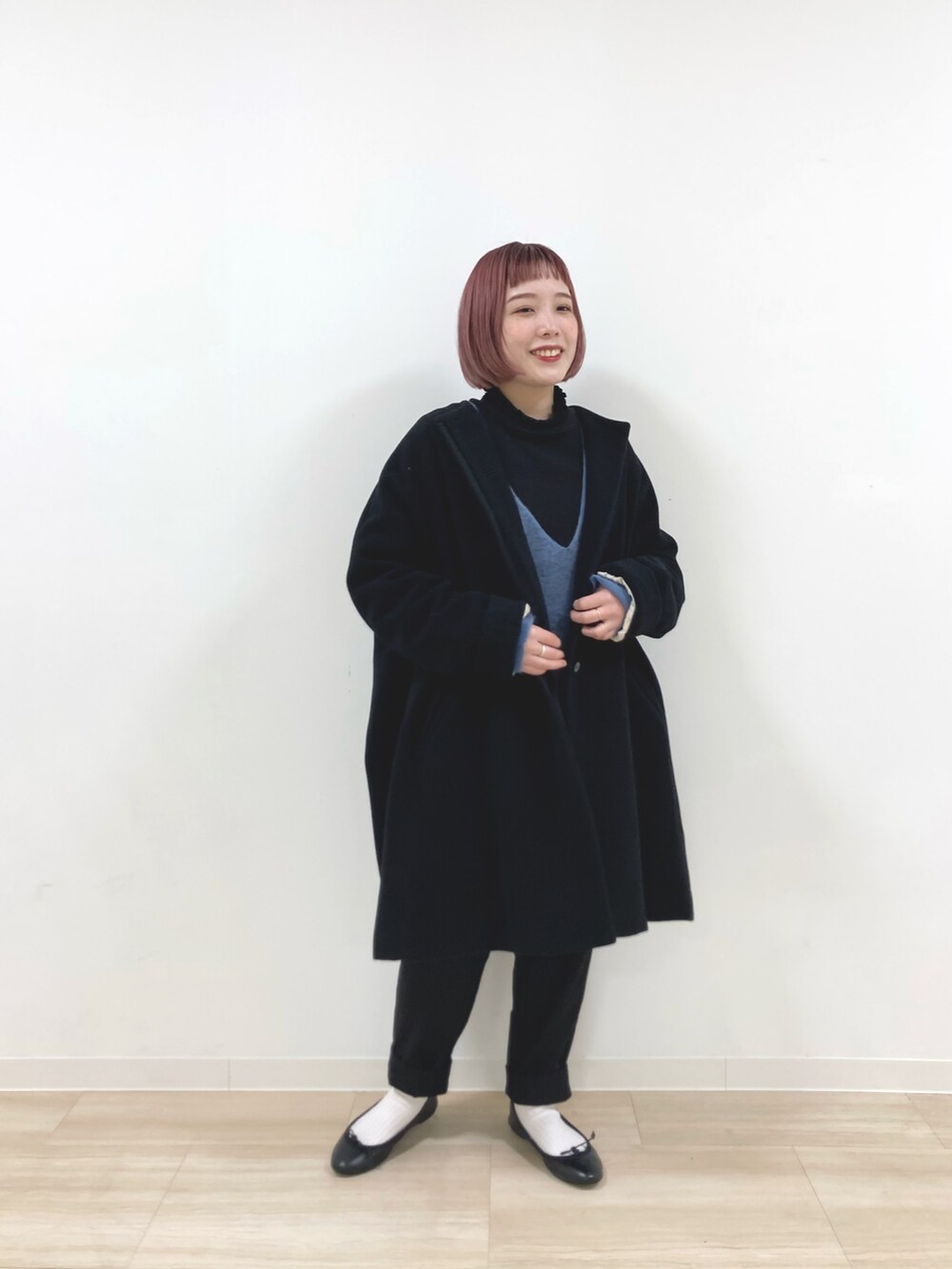 ブラック系のノーカラーコート、ブラック系のTシャツ/カットソー、ブルー系のニット/セーターを着用したレディースの冬コーディネートの2枚目の写真