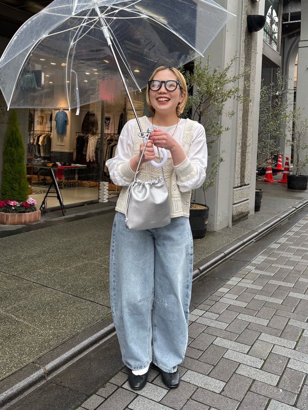 シルバー系のショルダーバッグ、ブルー系のデニムパンツ、ホワイト系のニット/セーターを着用したレディースの春コーディネートの2枚目の写真