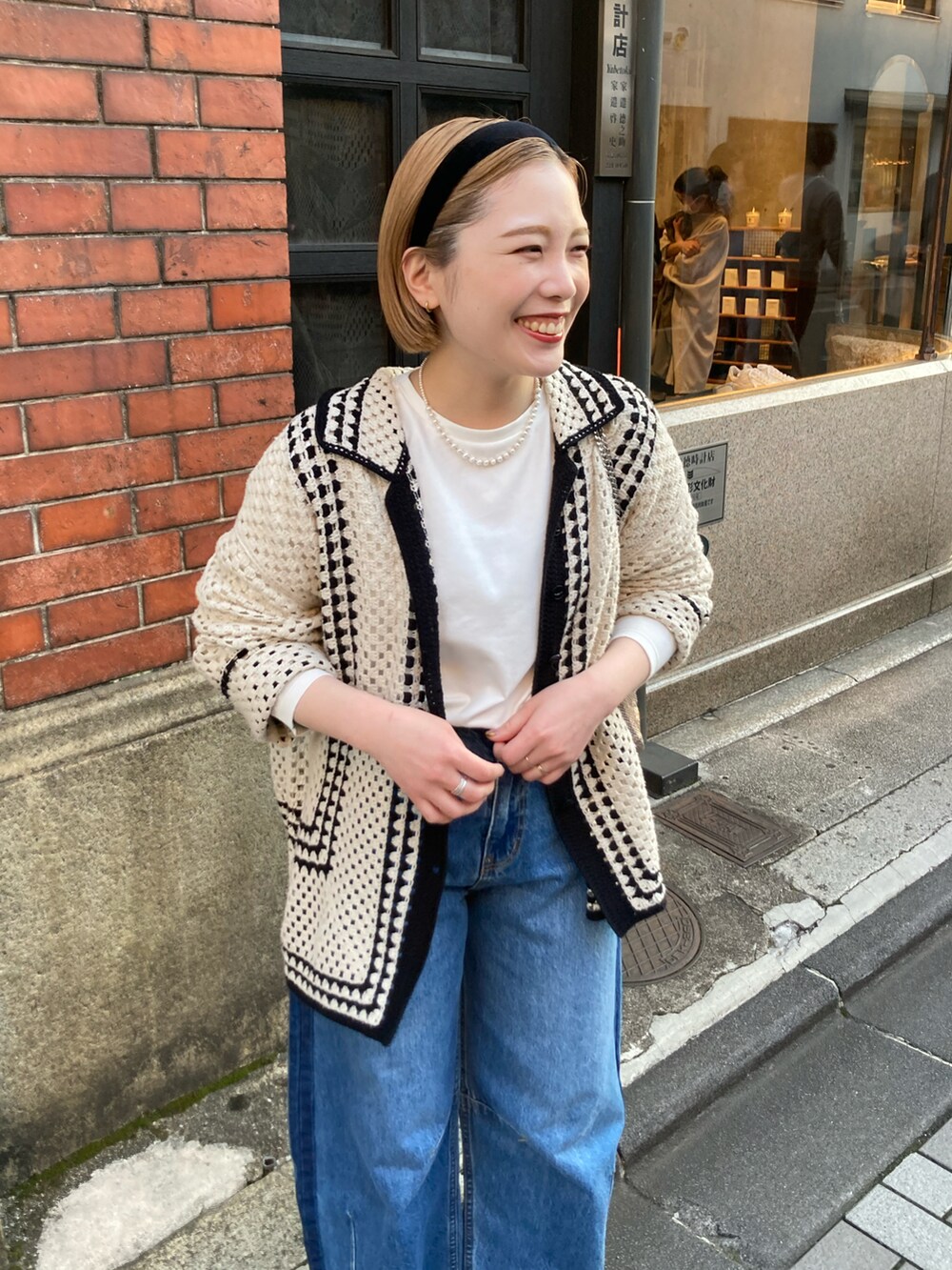 ブラック系のブーツ、ブルー系のデニムパンツ、ホワイト系のカーディガン/ボレロを着用したレディースの春コーディネートの3枚目の写真