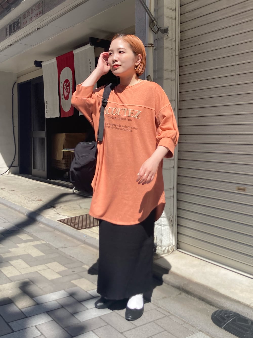 ブラック系のスカート、オレンジ系のTシャツ/カットソー、オレンジ系のTシャツ/カットソーを着用したレディースの秋コーディネートの2枚目の写真