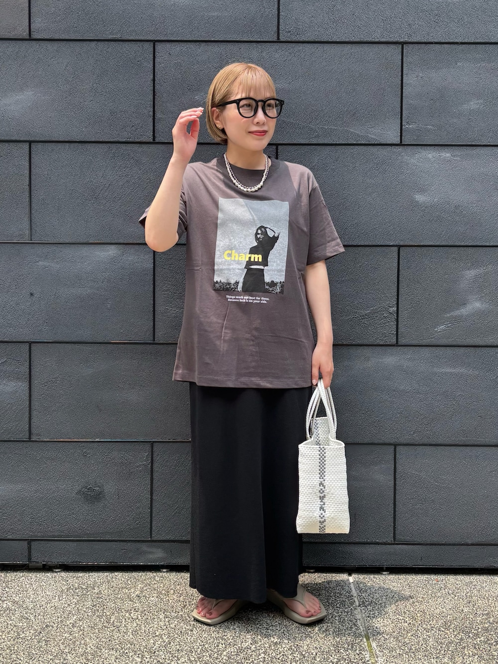 ブラック系のスカート、ベージュ系のサンダル、グレー系のTシャツ/カットソーを着用したレディースの夏コーディネートの2枚目の写真