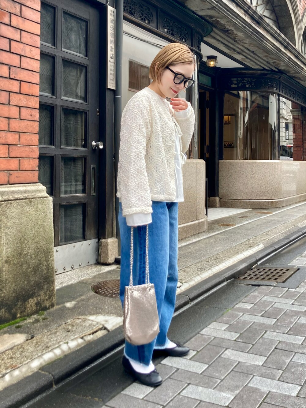 ブルー系のデニムパンツ、ゴールド系のショルダーバッグ、ホワイト系のシャツ/ブラウスを着用したレディースの春コーディネートの2枚目の写真