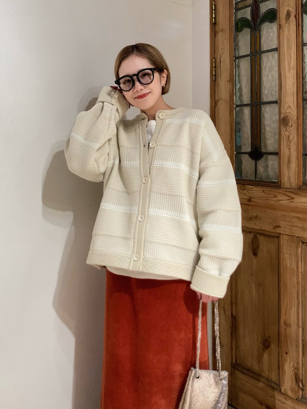 ブラック系のブーツ、ゴールド系のショルダーバッグ、オレンジ系のスカートを着用したレディースの冬コーディネートの4枚目の写真