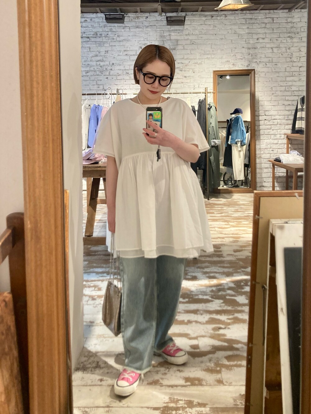 ブルー系のデニムパンツ、ゴールド系のショルダーバッグ、ブルー系のデニムパンツを着用したレディースの春コーディネートの4枚目の写真