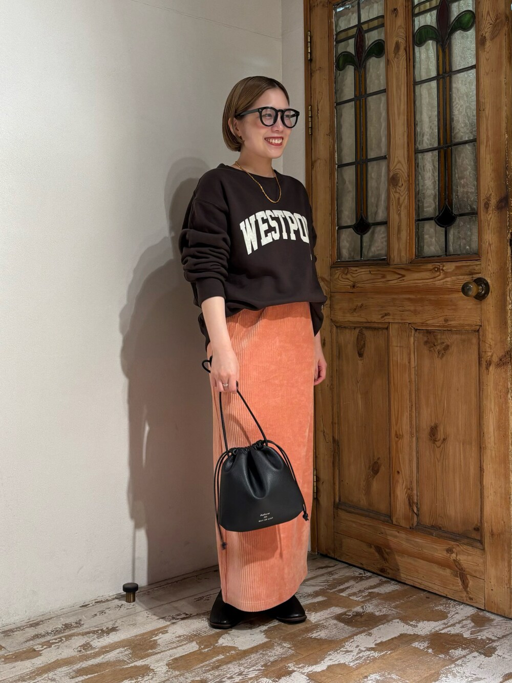 ピンク系のスカート、ブラック系のショルダーバッグ、ブラック系のブーツを着用したレディースの秋コーディネートの3枚目の写真