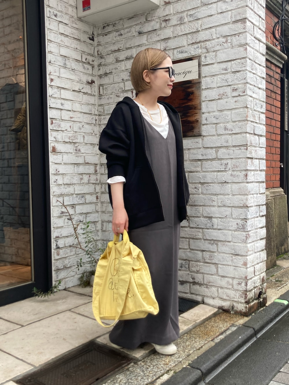 ベージュ系のスニーカー、イエロー系のトートバッグ、グレー系のワンピースを着用したレディースの秋コーディネートの3枚目の写真