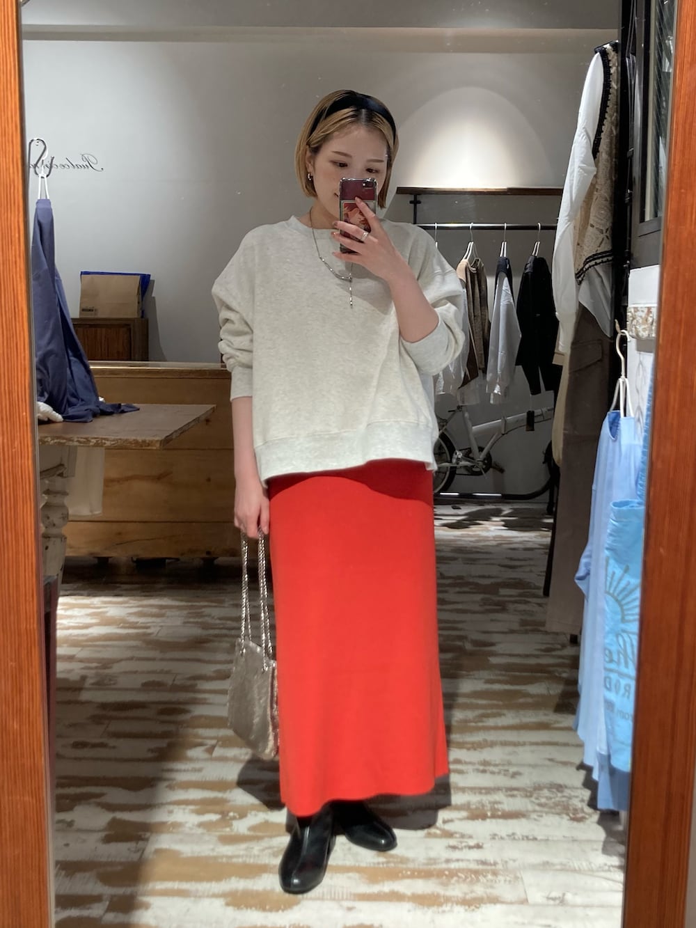 オレンジ系のスカート、ゴールド系のショルダーバッグ、ベージュ系のスウェットを着用したレディースの秋コーディネートの4枚目の写真