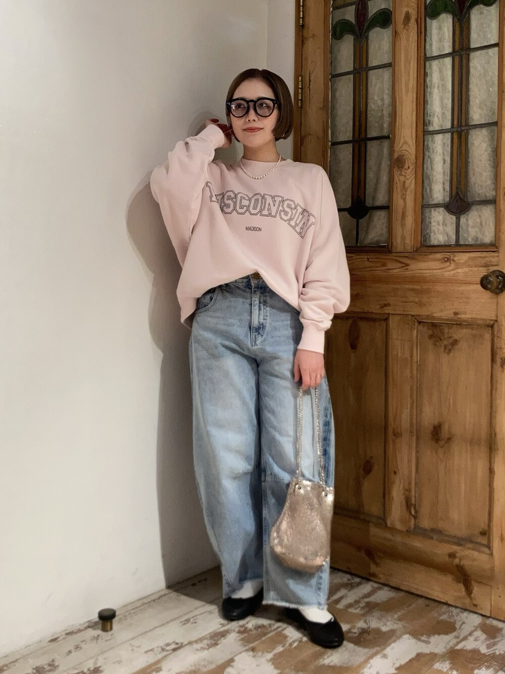 ブルー系のデニムパンツ、ピンク系のスウェット、ゴールド系のショルダーバッグを着用したレディースの冬コーディネートの3枚目の写真