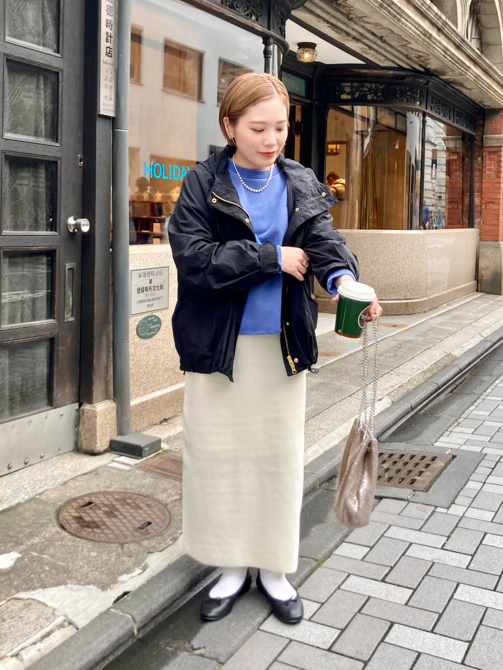 ホワイト系のスカート、ブルー系のスウェット、ブラック系のマウンテンパーカーを着用したレディースの冬コーディネートの2枚目の写真