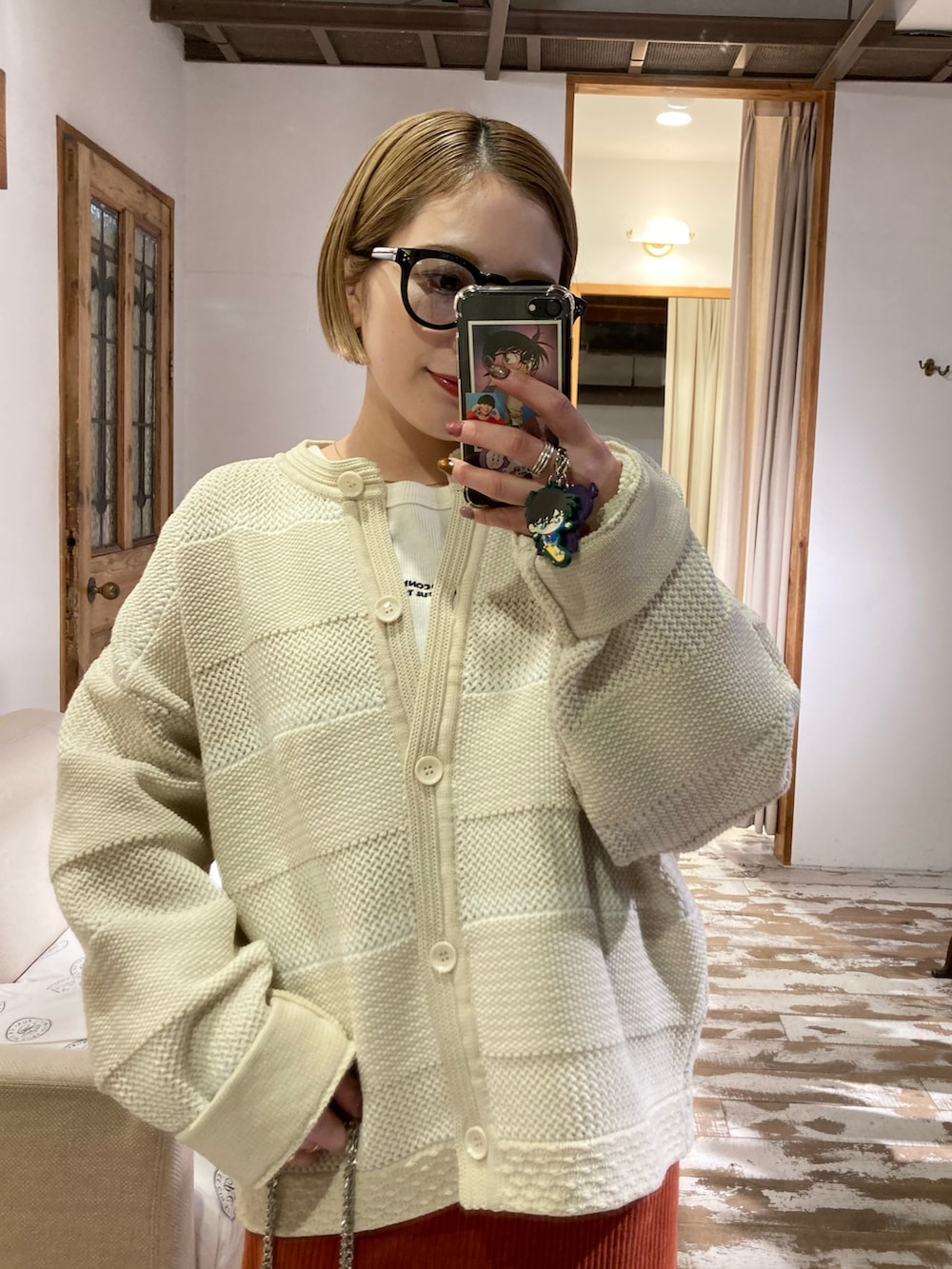 ブラック系のブーツ、ゴールド系のショルダーバッグ、オレンジ系のスカートを着用したレディースの冬コーディネートの5枚目の写真