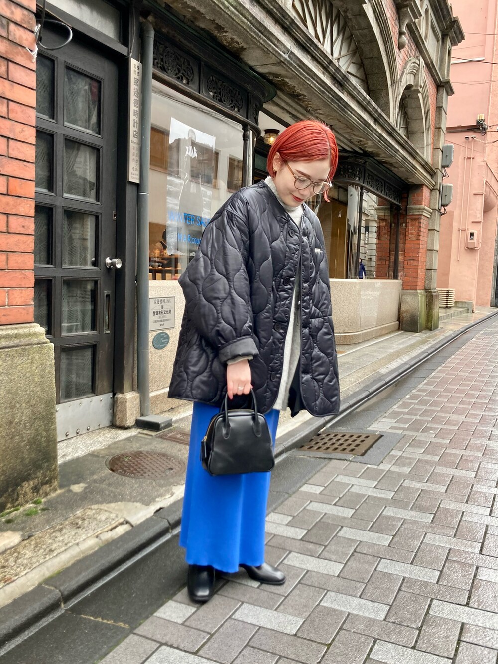 ブルー系のスカート、ブラック系のその他アウター、ベージュ系のニット/セーターを着用したレディースの冬コーディネートの3枚目の写真