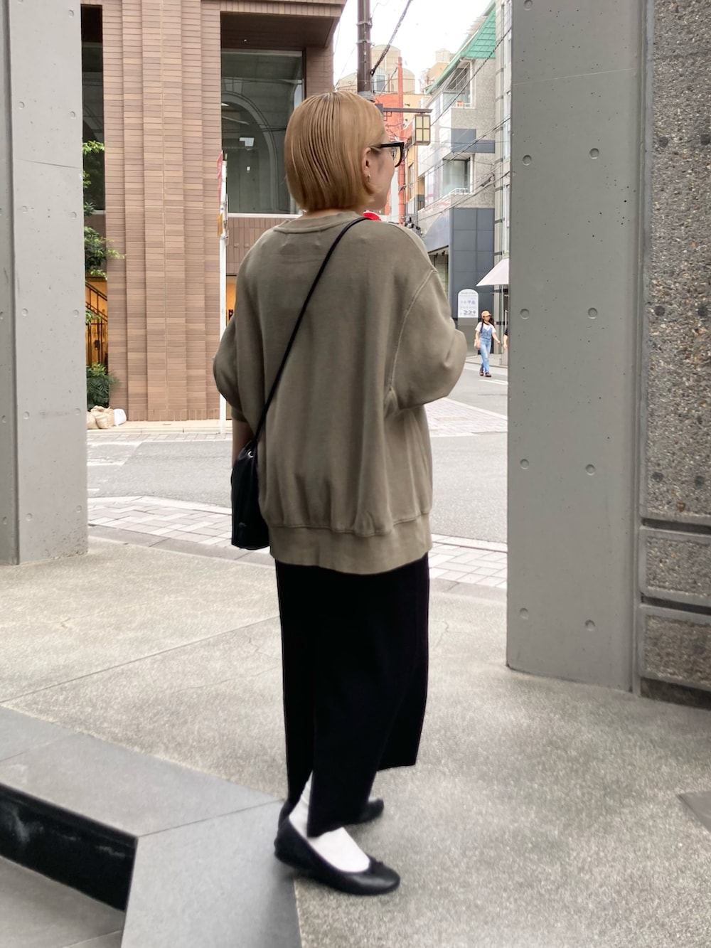 ブラック系のスカート、ベージュ系のスウェット、ブラック系のショルダーバッグを着用したレディースの秋コーディネートの2枚目の写真