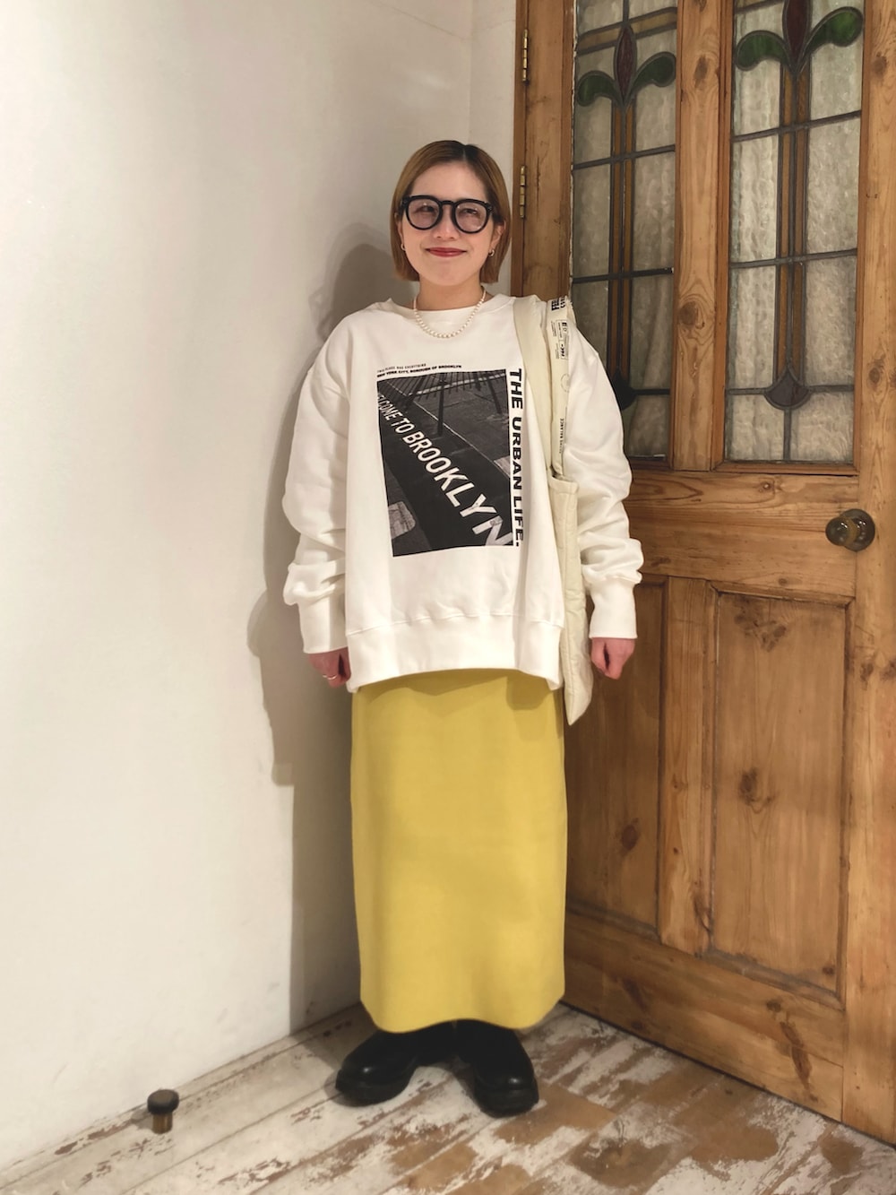 ブラック系のブーツ、イエロー系のスカート、ホワイト系のスウェットを着用したレディースの冬コーディネートの3枚目の写真