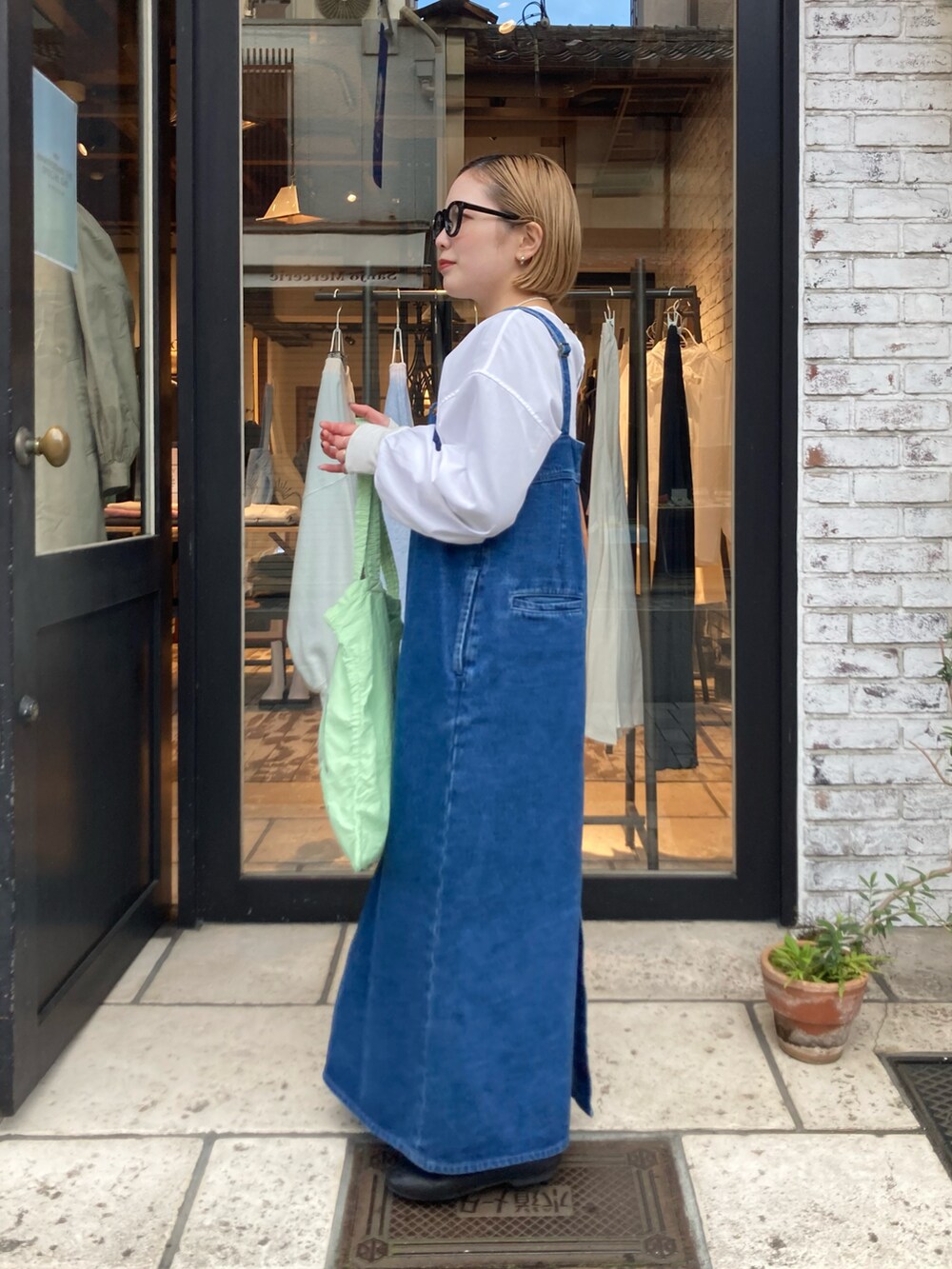 ブルー系のジャンパースカート、グリーン系のバッグ、ホワイト系のシャツ/ブラウスを着用したレディースの冬コーディネートの3枚目の写真