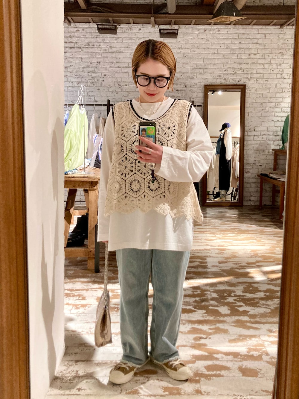 ブルー系のデニムパンツ、ゴールド系のショルダーバッグ、その他のトップスを着用したレディースの春コーディネートの3枚目の写真