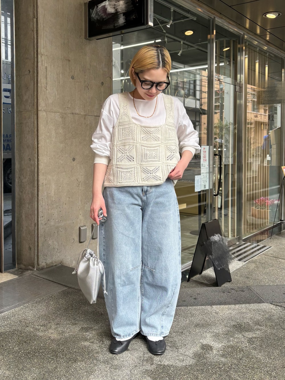 シルバー系のショルダーバッグ、ブルー系のデニムパンツ、ホワイト系のニット/セーターを着用したレディースの春コーディネートの3枚目の写真