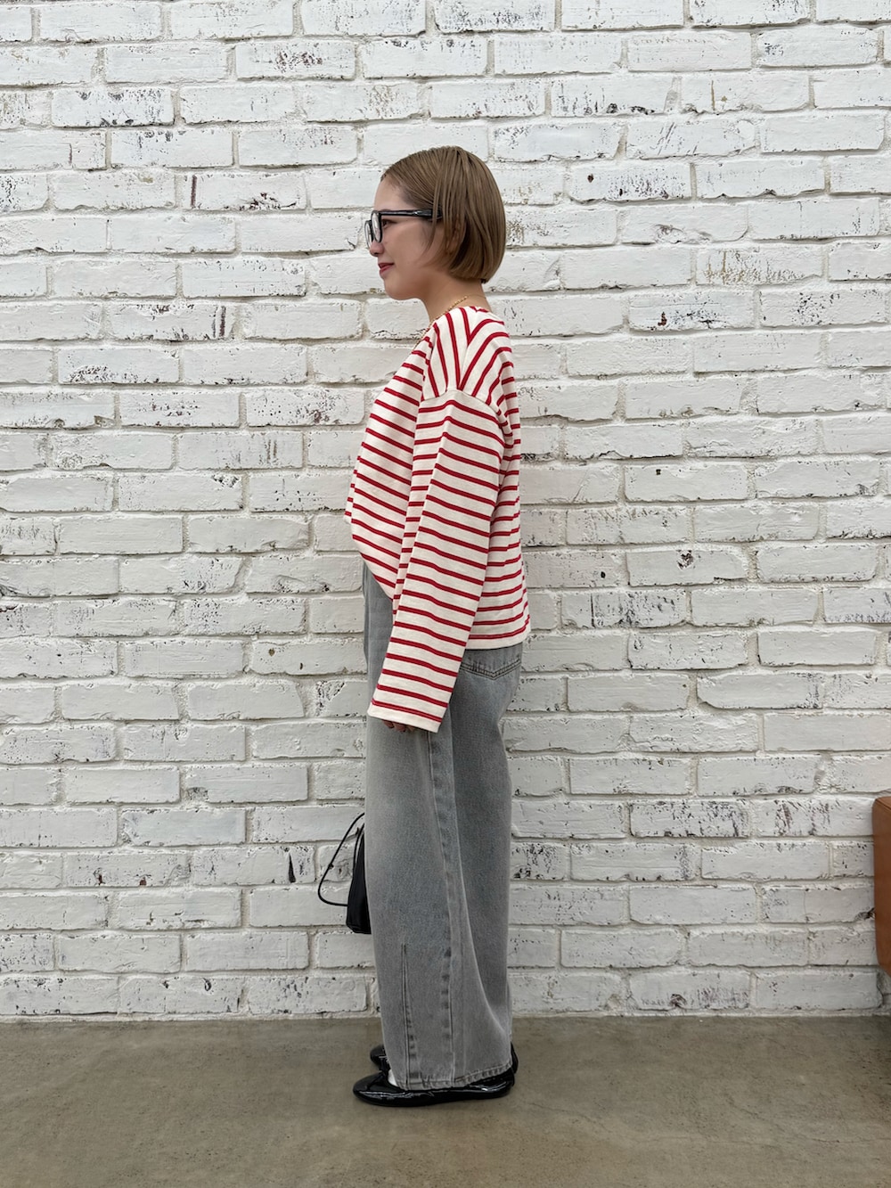 グレー系のデニムパンツ、ブラック系のショルダーバッグ、ゴールド系のネックレスを着用したレディースの冬コーディネートの2枚目の写真