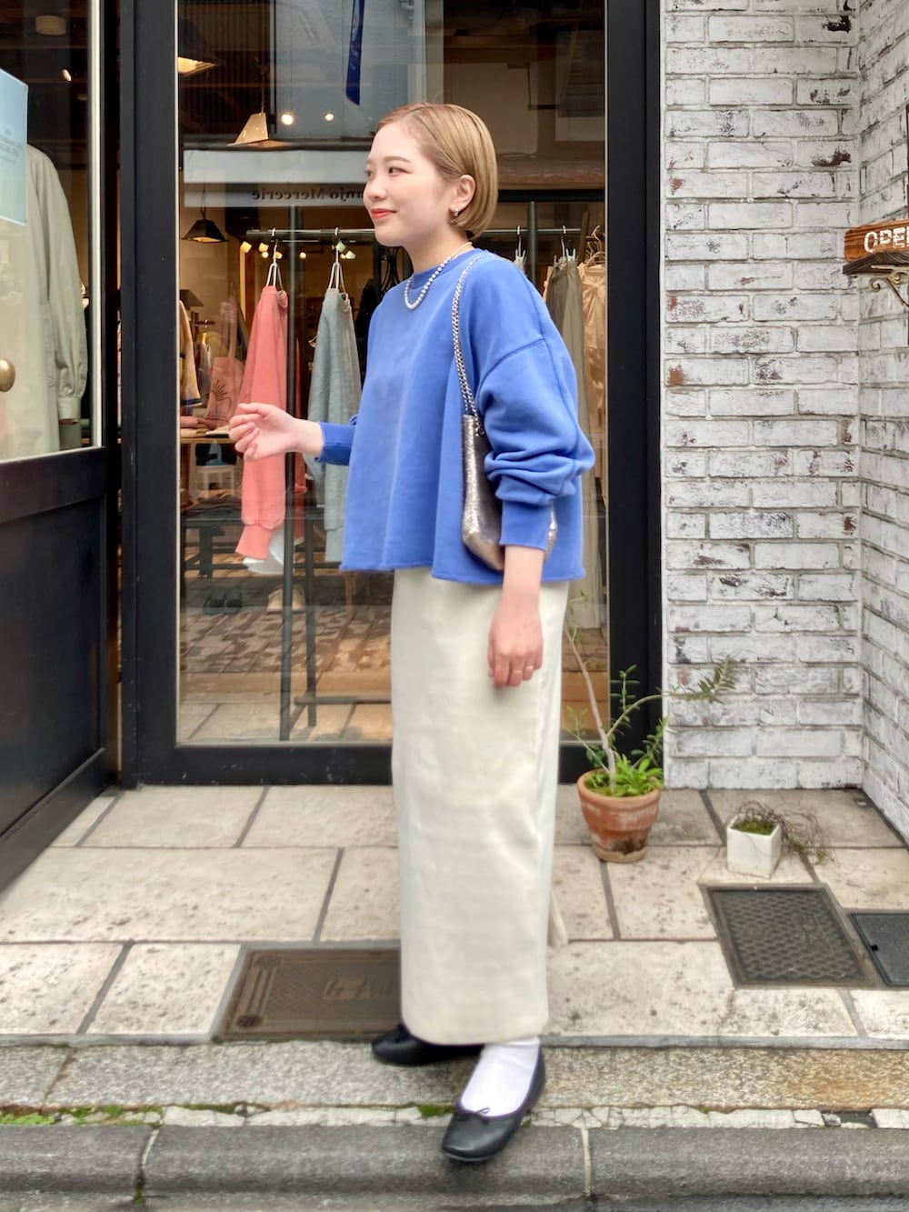 ホワイト系のスカート、ブルー系のスウェット、ブラック系のマウンテンパーカーを着用したレディースの冬コーディネートの3枚目の写真