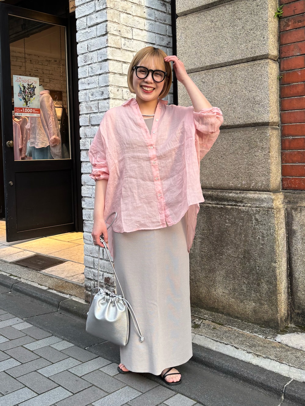 ピンク系のシャツ/ブラウス、グレー系のスカート、シルバー系のショルダーバッグを着用したレディースの春コーディネートの2枚目の写真
