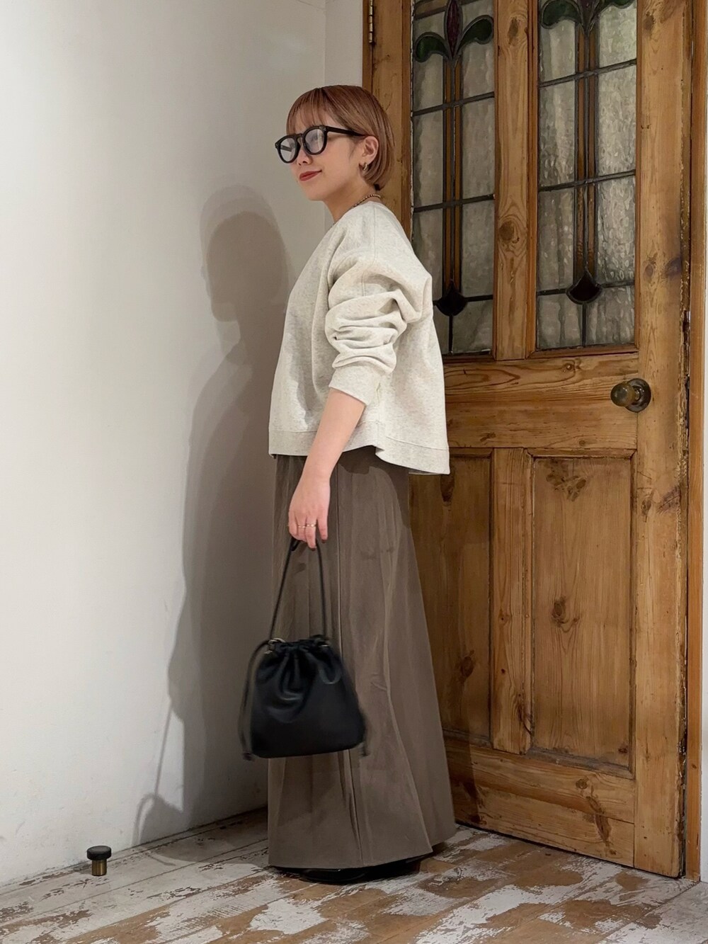 ベージュ系のTシャツ/カットソー、グリーン系のスカート、ブラック系のショルダーバッグを着用したレディースの秋コーディネートの2枚目の写真