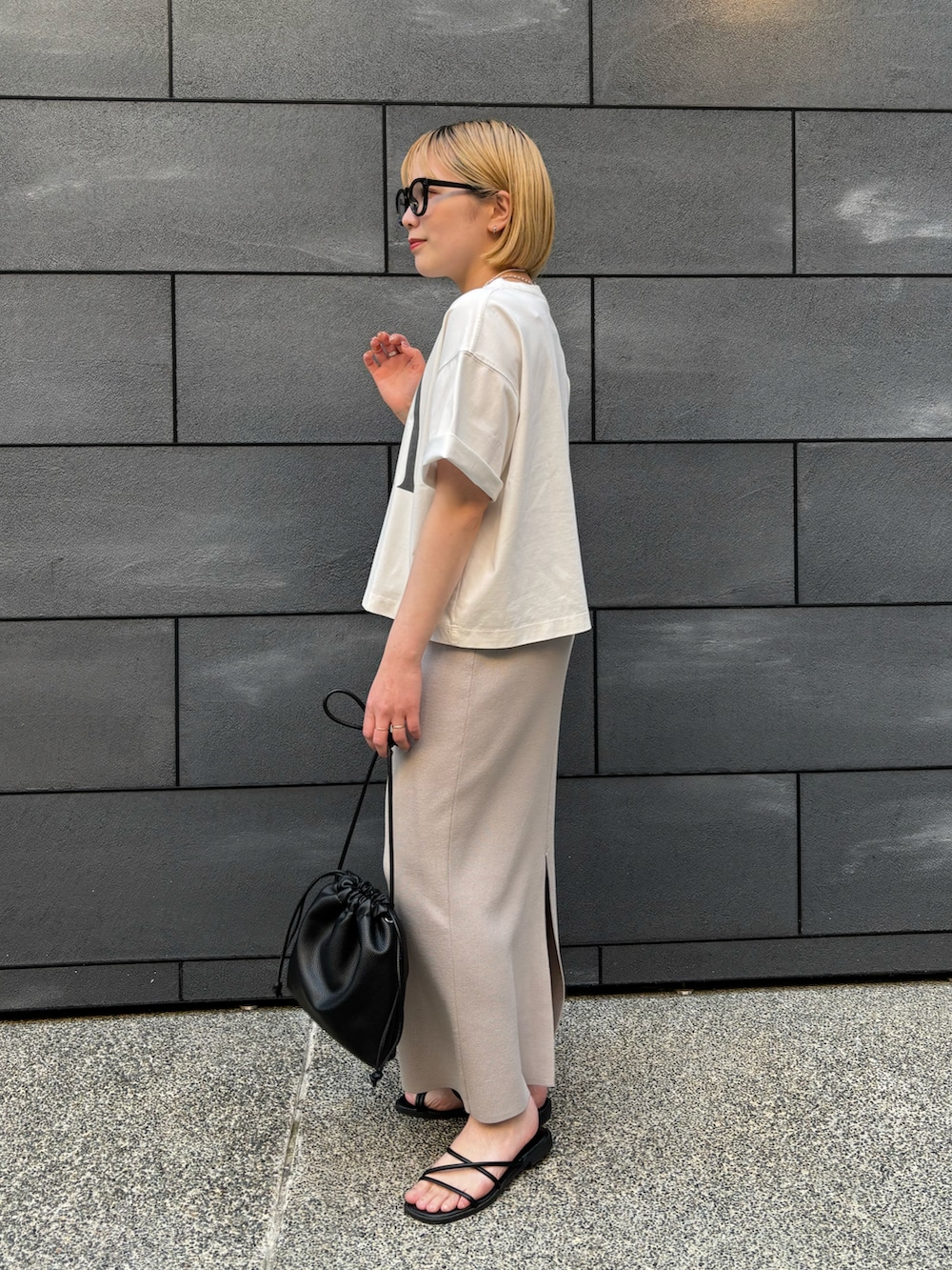 ブラック系のショルダーバッグ、グレー系のスカート、ホワイト系のTシャツ/カットソーを着用したレディースの春コーディネートの2枚目の写真