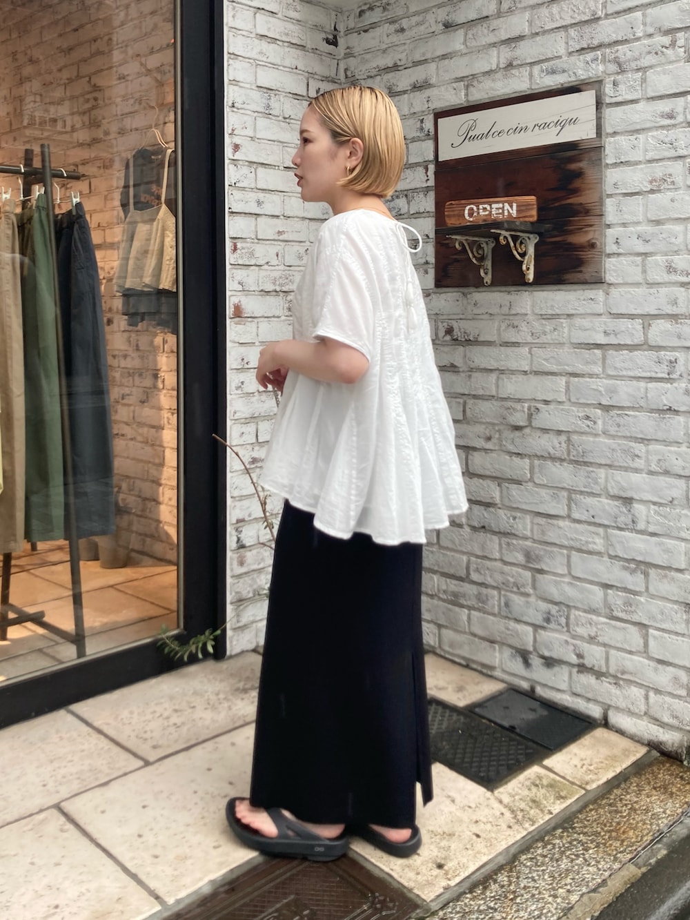 ホワイト系のシャツ/ブラウス、ブラック系のスカート、ブラック系のサンダルを着用したレディースの夏コーディネートの2枚目の写真