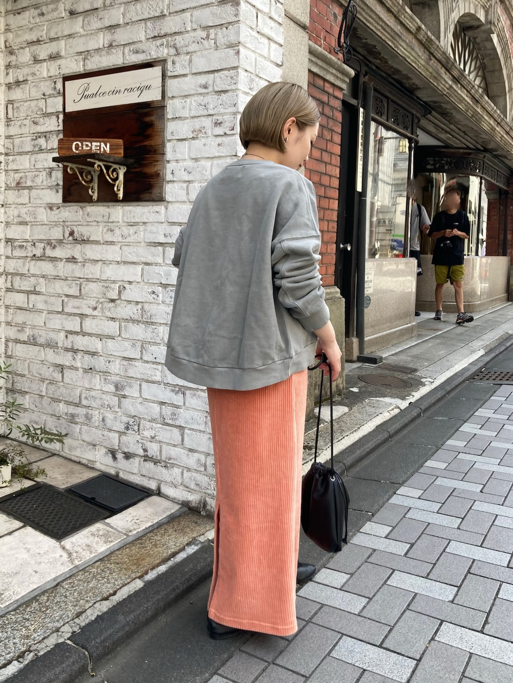 グレー系のスウェット、ピンク系のスカート、ブラック系のショルダーバッグを着用したレディースの秋コーディネートの2枚目の写真