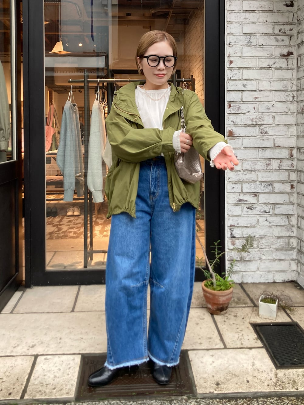 ブラック系のブーツ、ブルー系のデニムパンツ、ゴールド系のショルダーバッグを着用したレディースの冬コーディネートの2枚目の写真