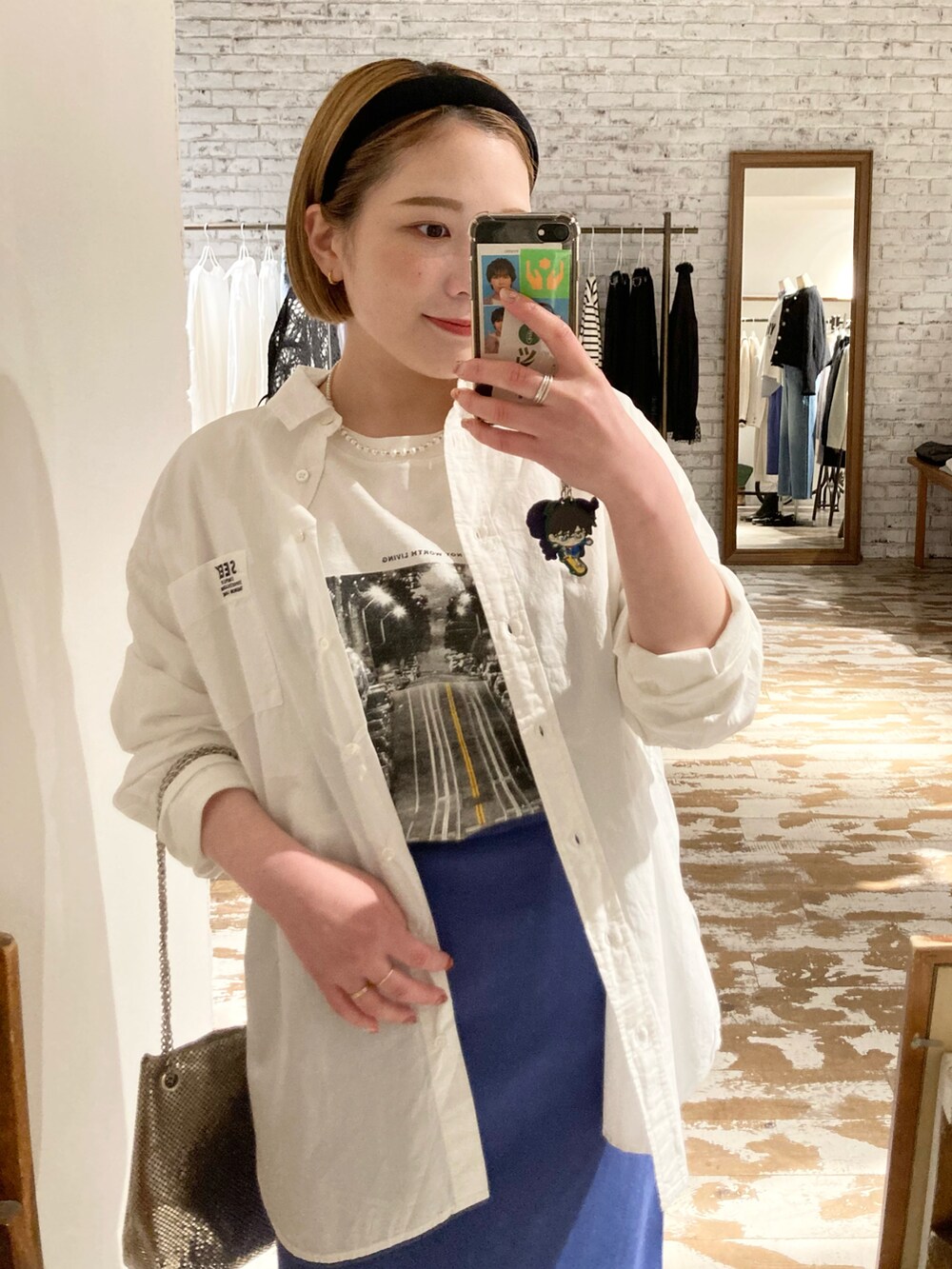 ブラック系のブーツ、ゴールド系のショルダーバッグ、ブルー系のスカートを着用したレディースの春コーディネートの5枚目の写真