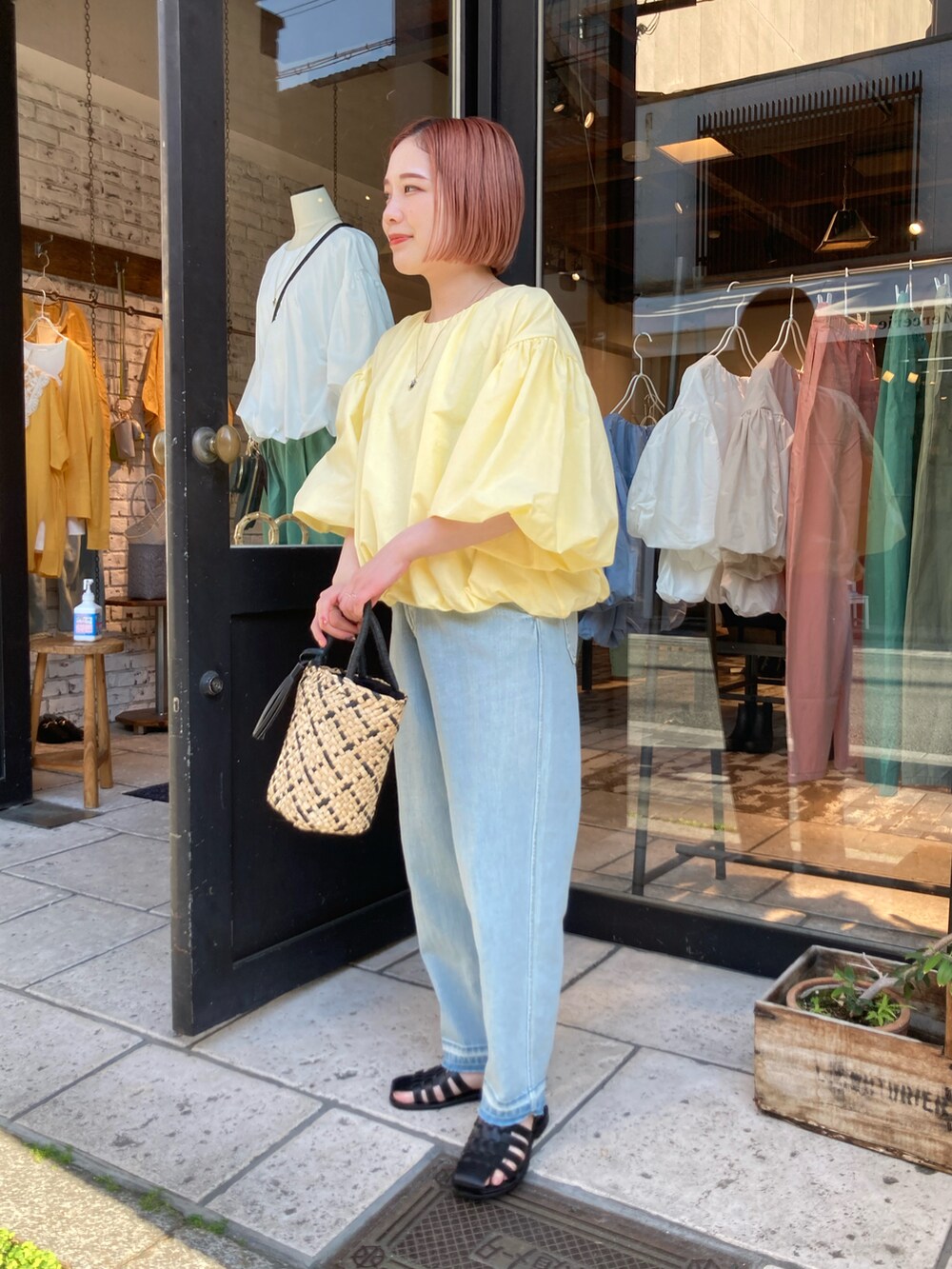 イエロー系のTシャツ/カットソー、ブルー系のデニムパンツ、ベージュ系のハンドバッグを着用したレディースの夏コーディネートの2枚目の写真