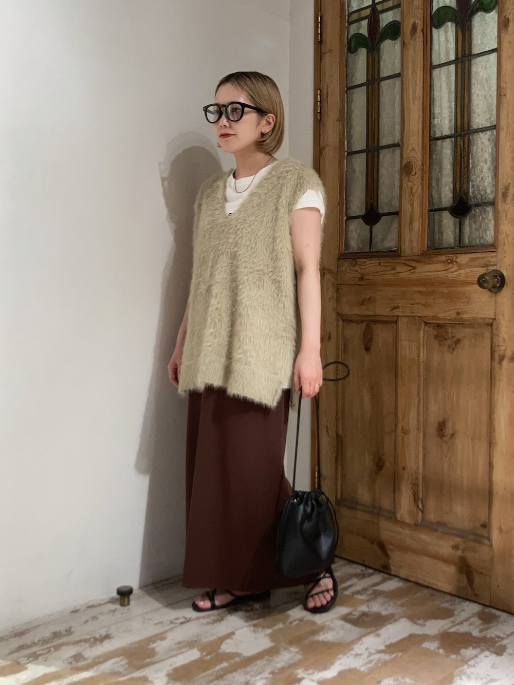 ブラック系のショルダーバッグ、ブラウン系のスカート、ベージュ系のベストを着用したレディースの秋コーディネートの3枚目の写真