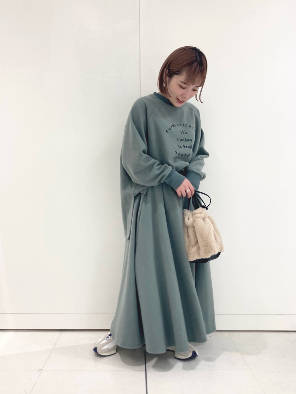 グリーン系のTシャツ/カットソー、グリーン系のスカート、ベージュ系のスニーカーを着用したレディースの秋コーディネートの2枚目の写真