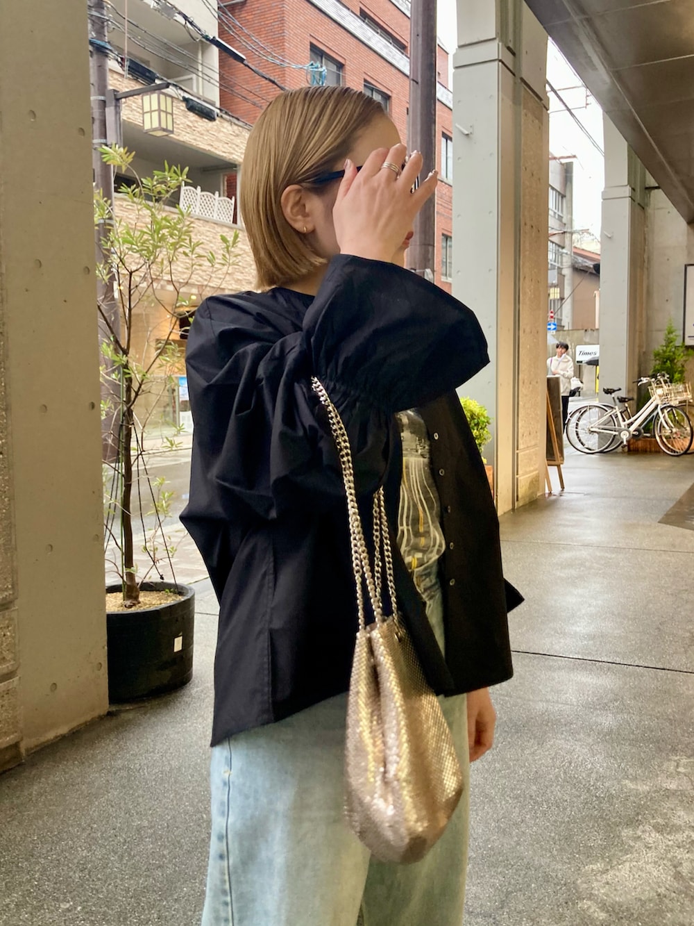 ブルー系のデニムパンツ、ゴールド系のショルダーバッグ、ブラック系のシャツ/ブラウスを着用したレディースの春コーディネートの4枚目の写真