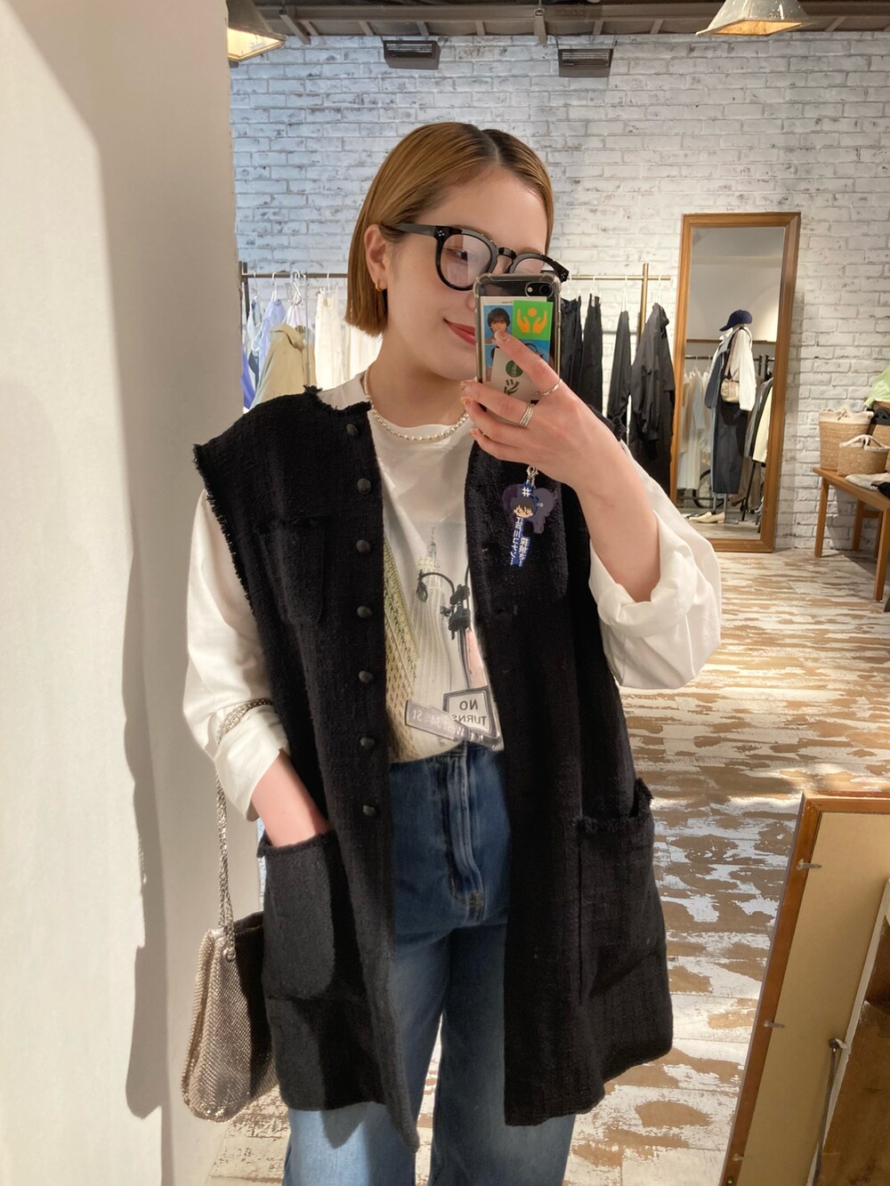 ブルー系のデニムパンツ、ホワイト系のTシャツ/カットソー、ブラック系のベストを着用したレディースの春コーディネートの5枚目の写真