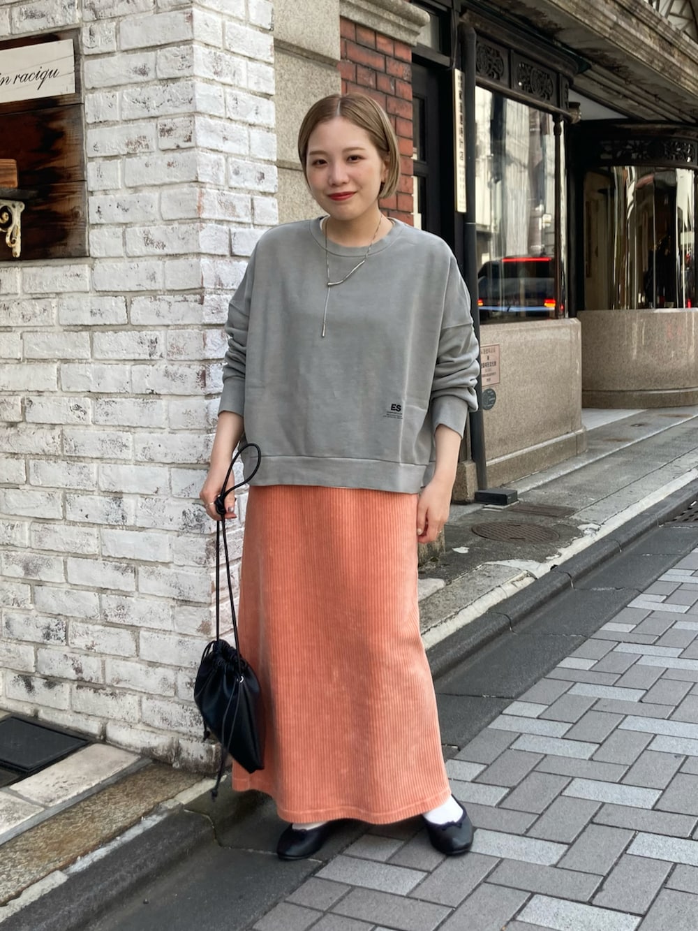 グレー系のスウェット、ピンク系のスカート、ブラック系のショルダーバッグを着用したレディースの秋コーディネートの4枚目の写真