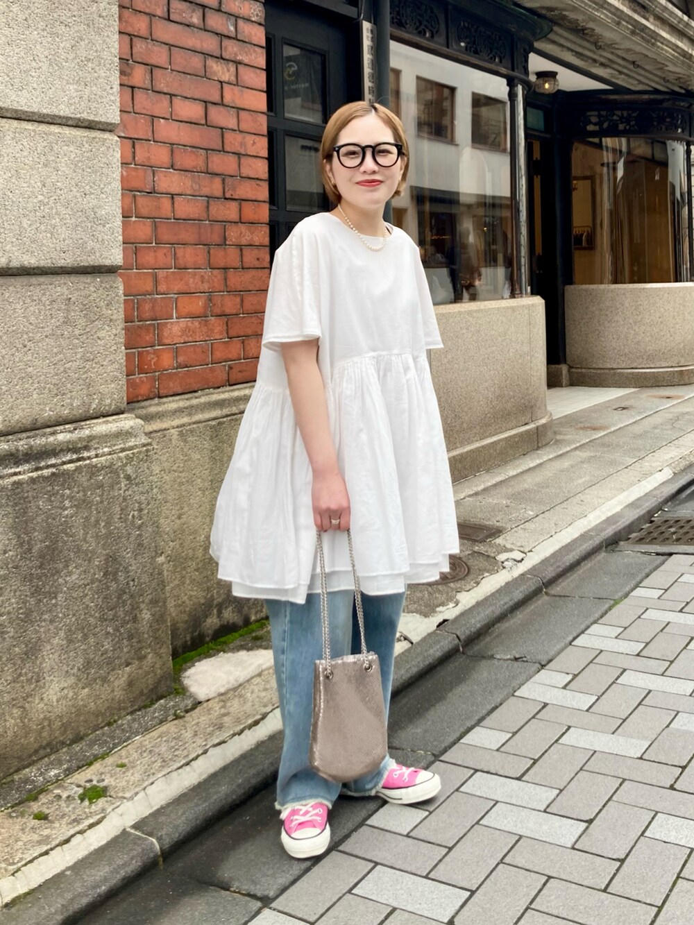 ブルー系のデニムパンツ、ゴールド系のショルダーバッグ、ブルー系のデニムパンツを着用したレディースの春コーディネートの2枚目の写真