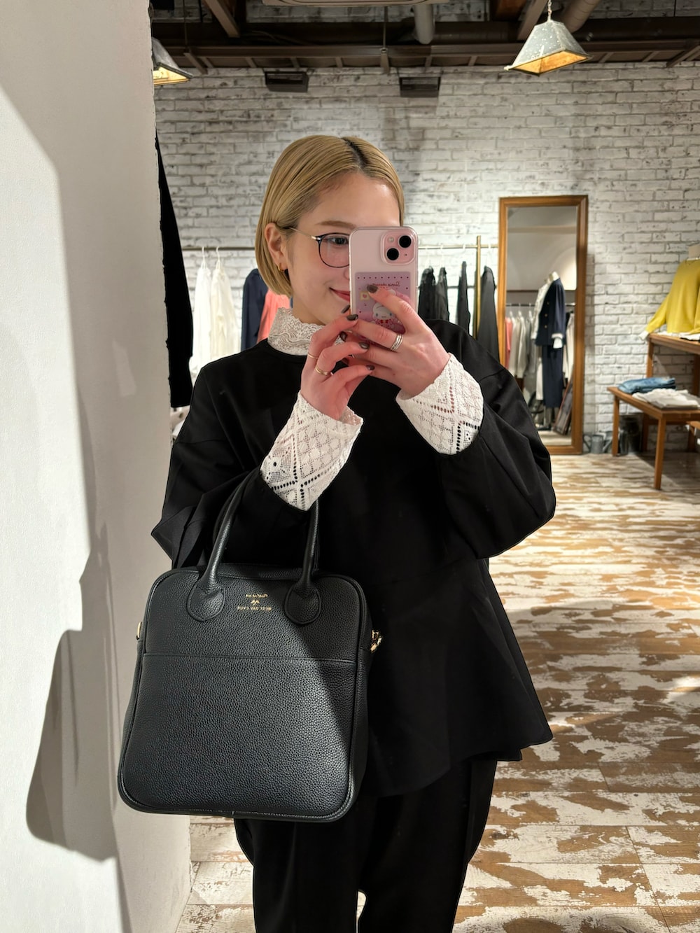 ブラック系のハンドバッグ、ブラック系のパンツ、ホワイト系のTシャツ/カットソーを着用したレディースの冬コーディネートの4枚目の写真