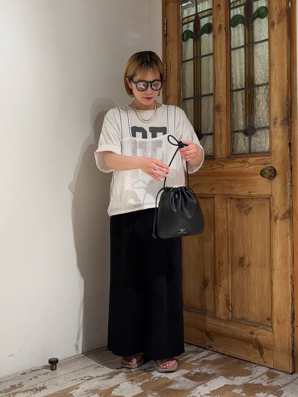 ブラック系のスカート、ホワイト系のベスト、ホワイト系のTシャツ/カットソーを着用したレディースの夏コーディネートの2枚目の写真