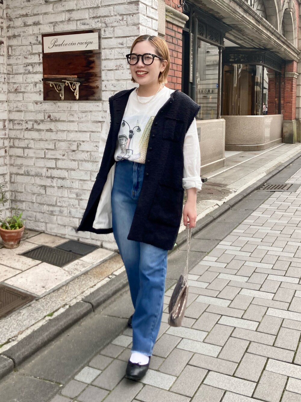 ブルー系のデニムパンツ、ホワイト系のTシャツ/カットソー、ブラック系のベストを着用したレディースの春コーディネートの3枚目の写真