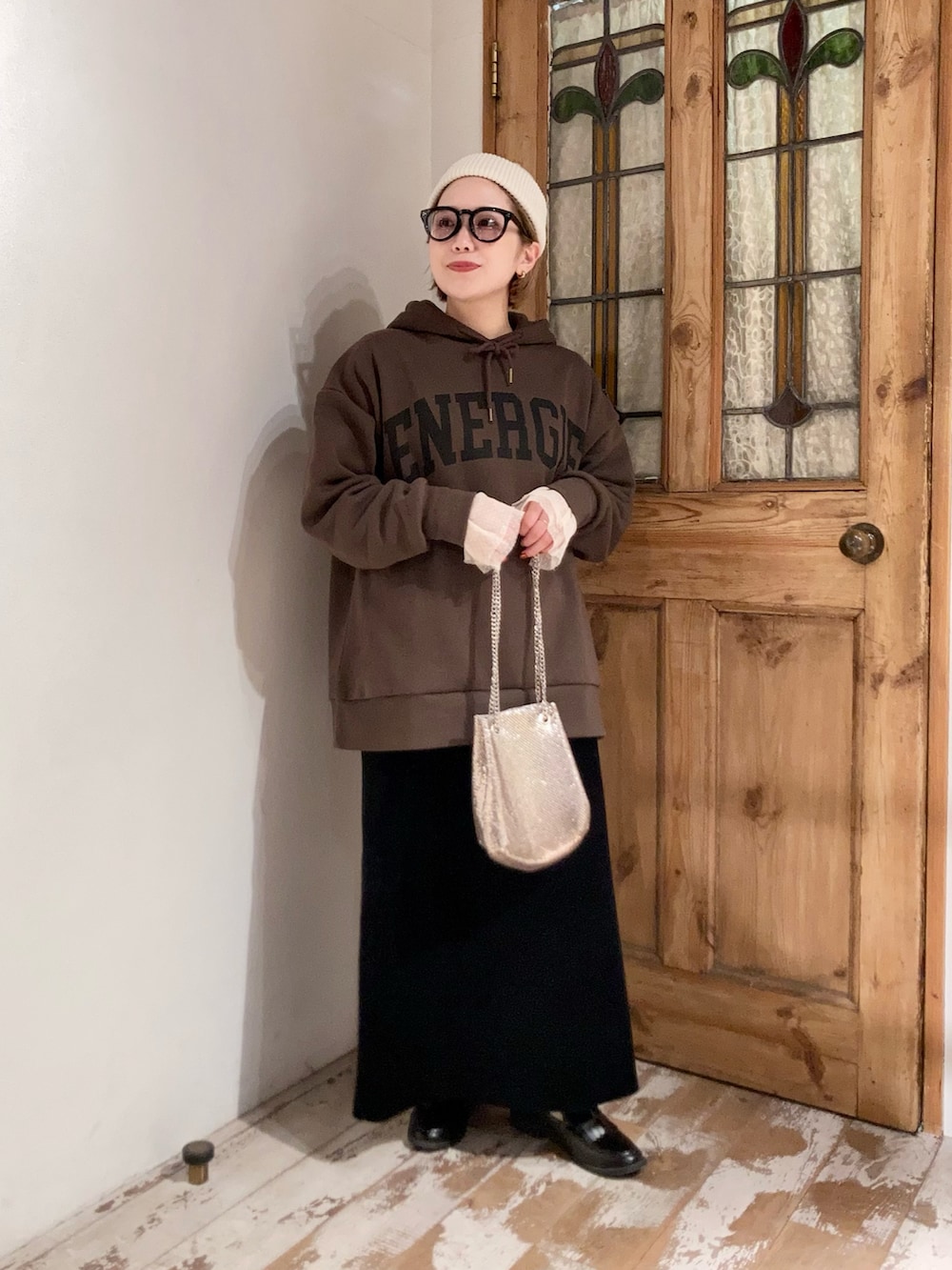 ブラウン系のパーカー、ブラック系のスカート、ゴールド系のショルダーバッグを着用したレディースの秋コーディネートの4枚目の写真